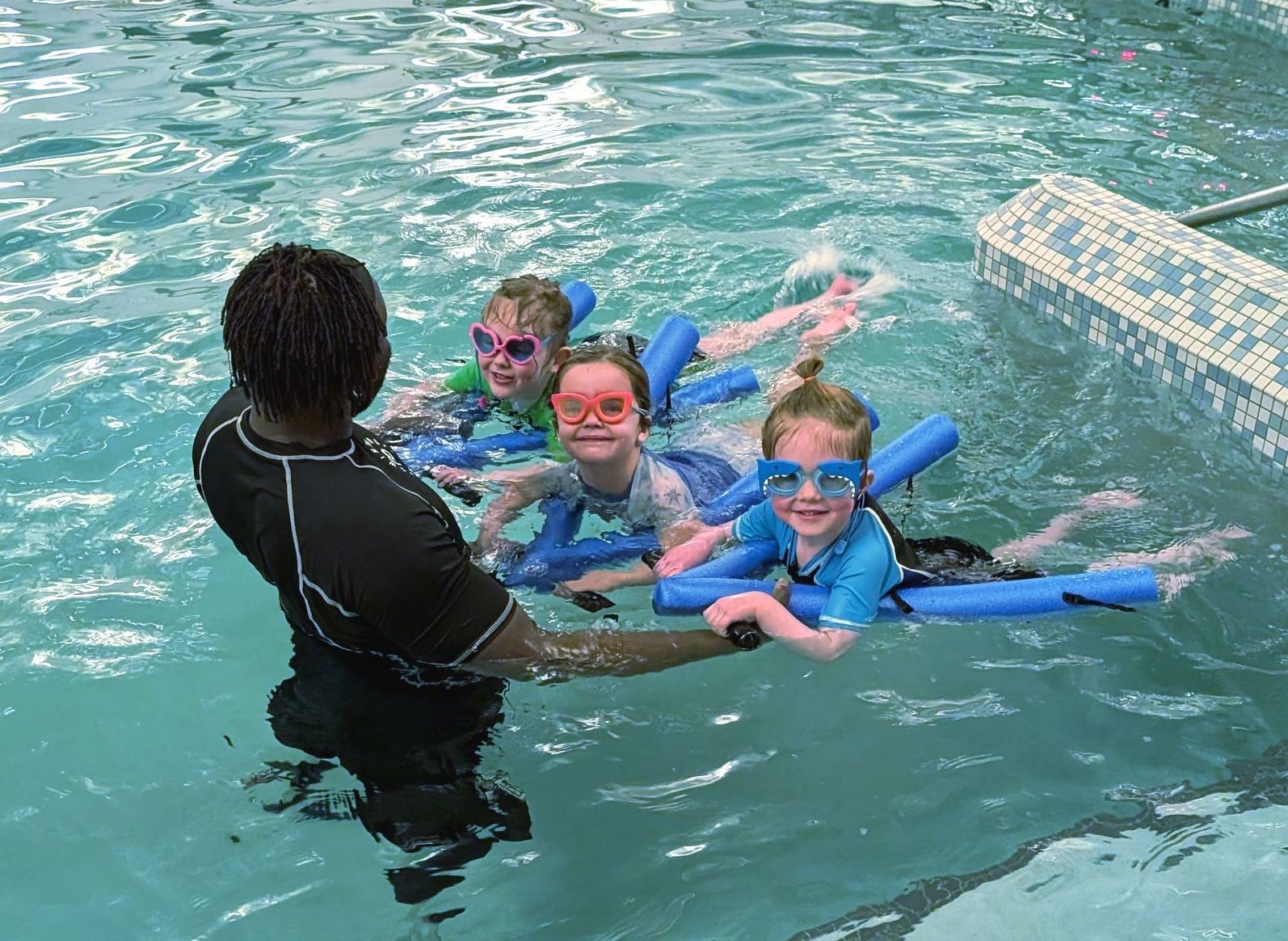 An instructor teaching a small group of young swimmers