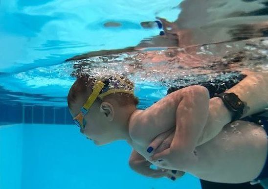 A baby discovering the water with an instructor